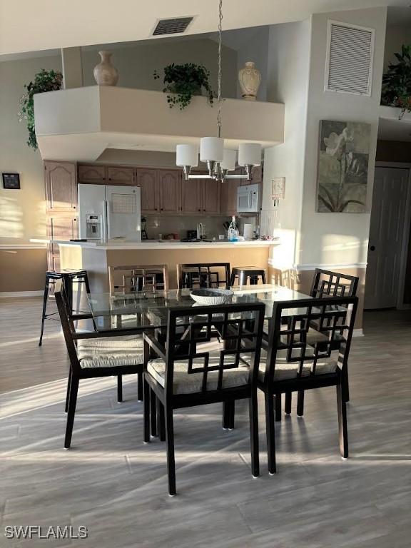 dining room featuring light hardwood / wood-style flooring, a chandelier, and a high ceiling