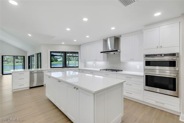 kitchen featuring stainless steel appliances, a kitchen island, white cabinets, and wall chimney exhaust hood