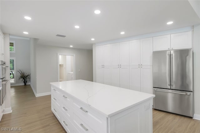 kitchen featuring high end fridge, light hardwood / wood-style flooring, white cabinets, and a kitchen island