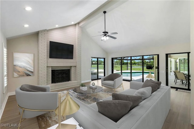 living room with high vaulted ceiling, beam ceiling, light hardwood / wood-style floors, and a brick fireplace