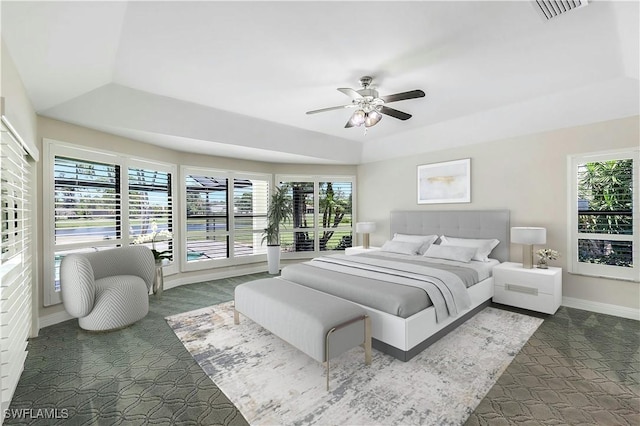 bedroom with ceiling fan, a raised ceiling, and multiple windows