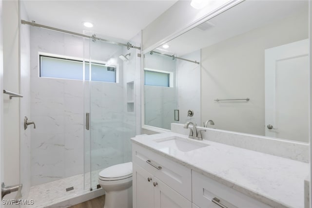 bathroom featuring vanity, toilet, and a shower with shower door