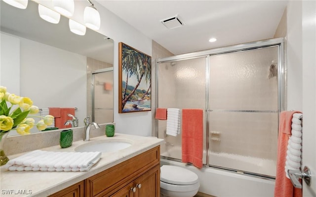 full bathroom with bath / shower combo with glass door, vanity, and toilet