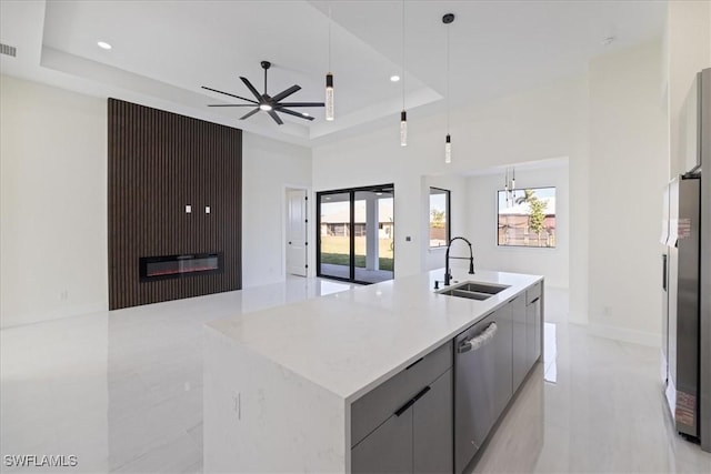 kitchen with sink, dishwasher, gray cabinets, a raised ceiling, and a kitchen island with sink