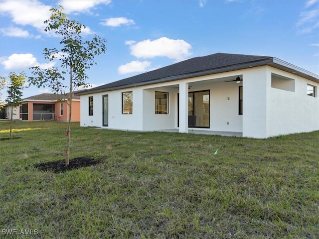 rear view of house with ceiling fan and a lawn