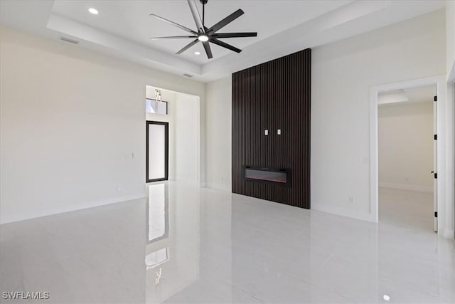 spare room with ceiling fan and a raised ceiling