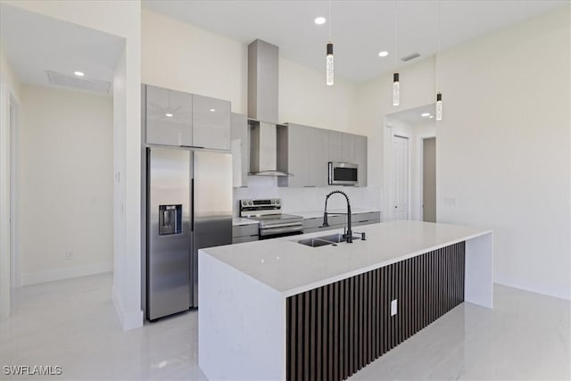 kitchen with wall chimney exhaust hood, sink, gray cabinetry, hanging light fixtures, and appliances with stainless steel finishes