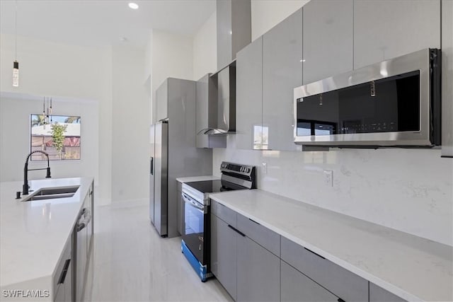 kitchen featuring gray cabinets, sink, hanging light fixtures, stainless steel appliances, and wall chimney exhaust hood