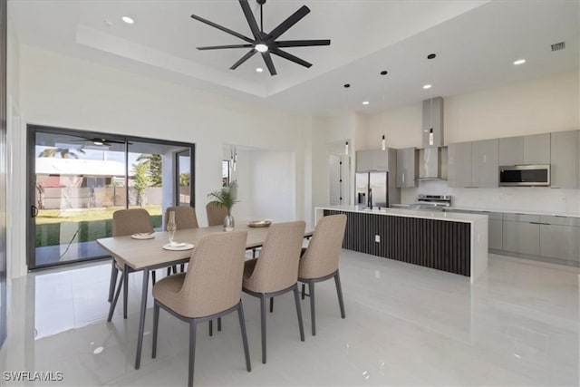 dining room with a high ceiling, ceiling fan, and a tray ceiling