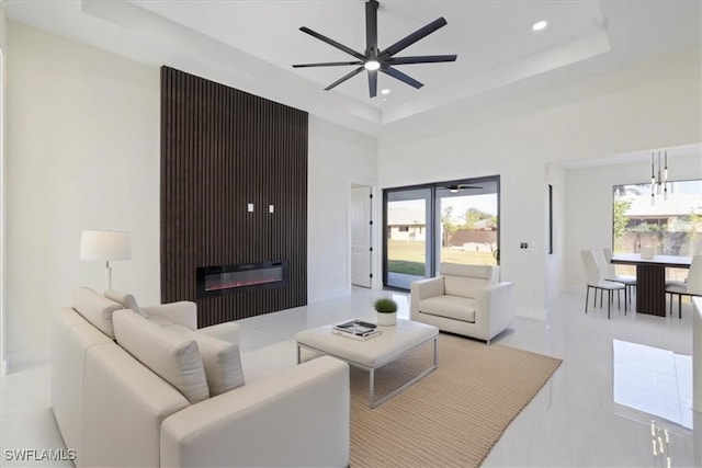 living room featuring a tray ceiling, ceiling fan, and a high ceiling