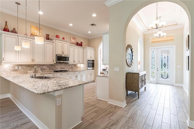 kitchen featuring stainless steel appliances, a peninsula, a sink, visible vents, and decorative light fixtures