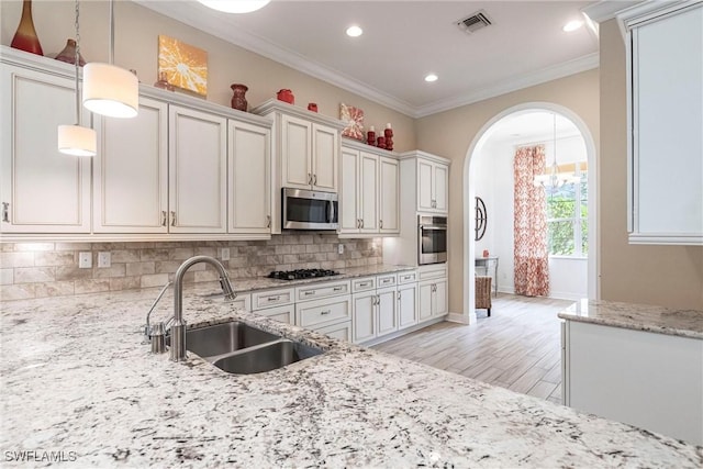 kitchen featuring tasteful backsplash, visible vents, hanging light fixtures, appliances with stainless steel finishes, and a sink