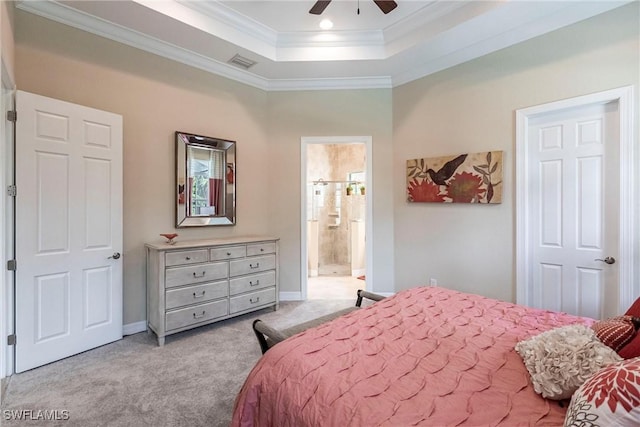 bedroom with a tray ceiling, crown molding, visible vents, light carpet, and connected bathroom