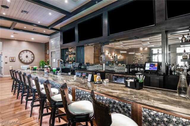 bar with beam ceiling, recessed lighting, visible vents, light wood-style floors, and a bar