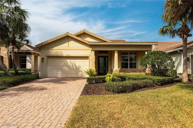 view of front of home with a garage, a front yard, decorative driveway, and stucco siding