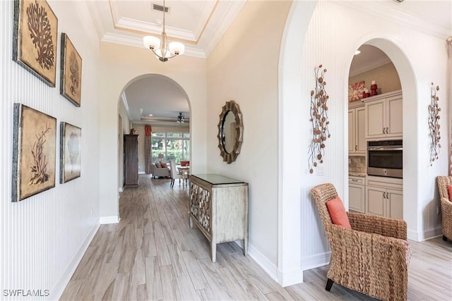 hall featuring light wood-style floors, visible vents, and crown molding