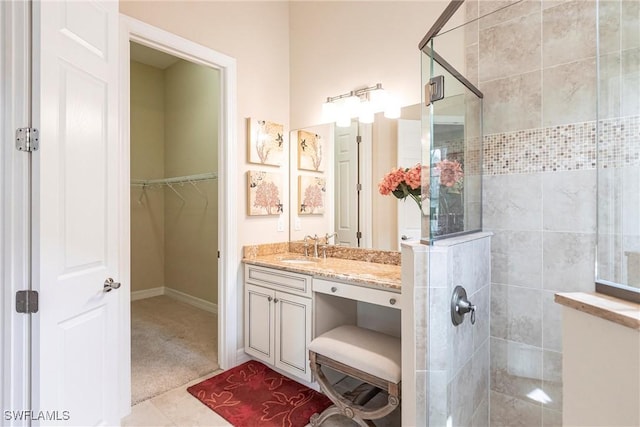 full bathroom featuring a stall shower, tile patterned floors, a walk in closet, and vanity