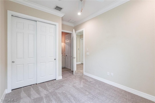 unfurnished bedroom featuring crown molding, a closet, visible vents, light carpet, and baseboards