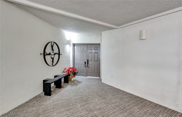 interior space featuring carpet flooring, beam ceiling, and a textured ceiling