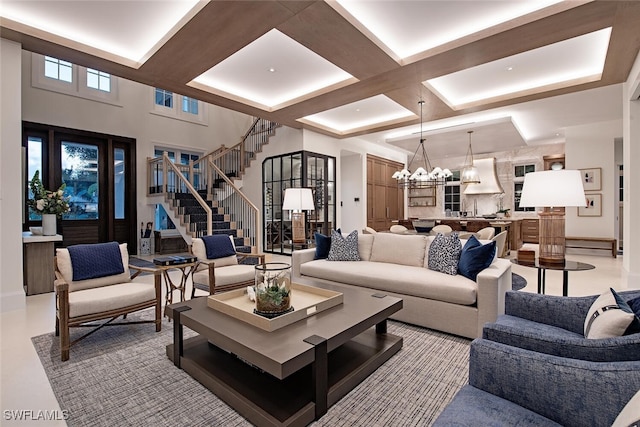 living room featuring beam ceiling, coffered ceiling, a chandelier, and a towering ceiling