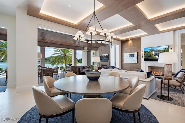 dining area featuring a large fireplace, a healthy amount of sunlight, coffered ceiling, and a notable chandelier