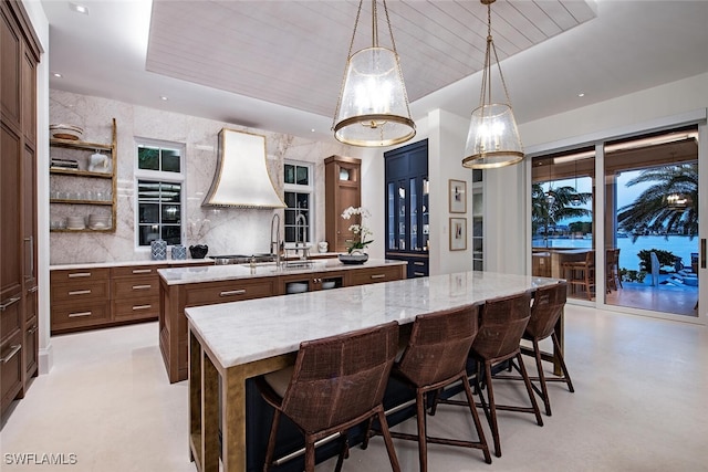 kitchen featuring a kitchen breakfast bar, pendant lighting, a large island, light stone countertops, and backsplash