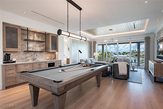 rec room with billiards, wet bar, a raised ceiling, and light wood-type flooring