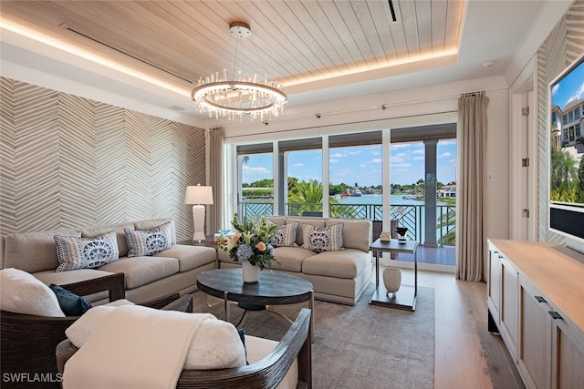 living room featuring a notable chandelier, wood ceiling, a raised ceiling, a water view, and a healthy amount of sunlight