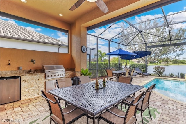 view of patio / terrace with a fenced in pool, a water view, glass enclosure, a grill, and exterior kitchen