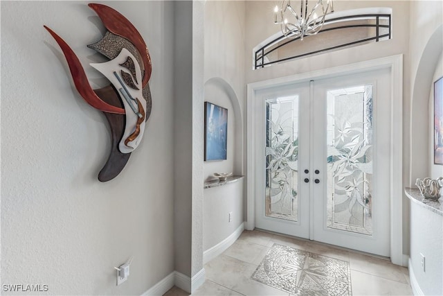 tiled foyer entrance featuring french doors and a chandelier