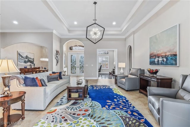 tiled living room with french doors, ornamental molding, a raised ceiling, and a notable chandelier