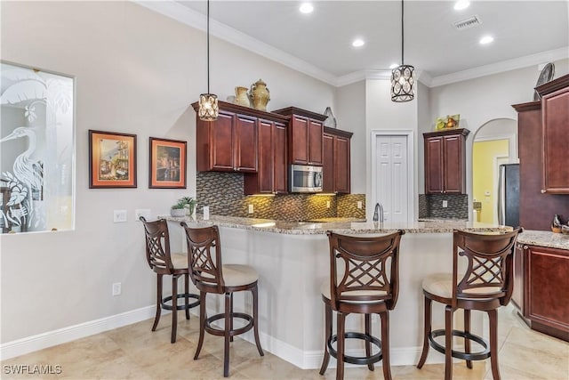 kitchen featuring a breakfast bar, stainless steel appliances, decorative light fixtures, and kitchen peninsula