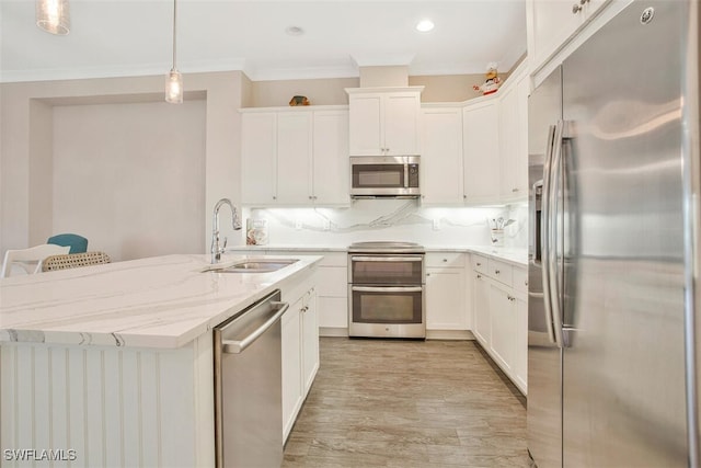 kitchen with appliances with stainless steel finishes, decorative light fixtures, sink, and white cabinets