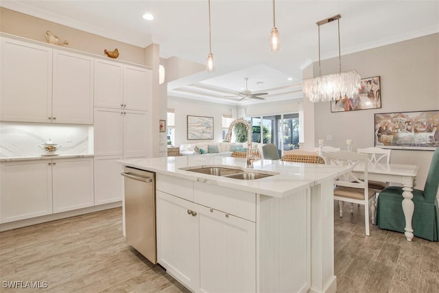 kitchen with stainless steel dishwasher, sink, a kitchen island with sink, and hanging light fixtures