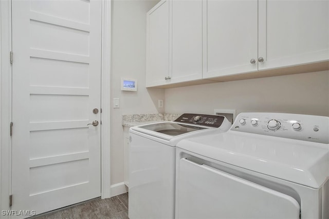 clothes washing area featuring dark wood-type flooring, cabinets, and washer and dryer