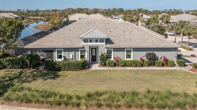 view of front of home with a front lawn, a water view, and glass enclosure