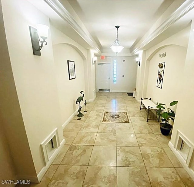 interior space with a raised ceiling, crown molding, and light tile patterned floors