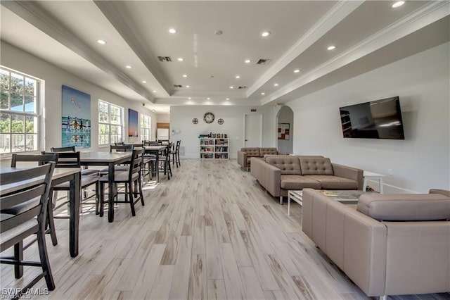 living room with ornamental molding, light wood-type flooring, and a tray ceiling