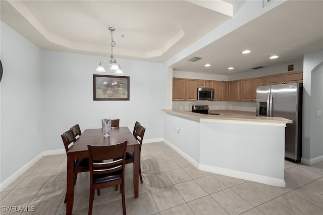 kitchen with light tile patterned flooring, stainless steel appliances, decorative light fixtures, and kitchen peninsula