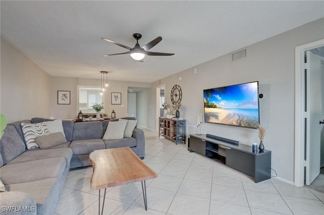 living area with light tile patterned floors, a textured ceiling, visible vents, and a ceiling fan