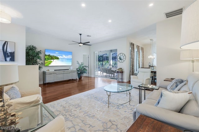 living room with hardwood / wood-style floors and ceiling fan with notable chandelier