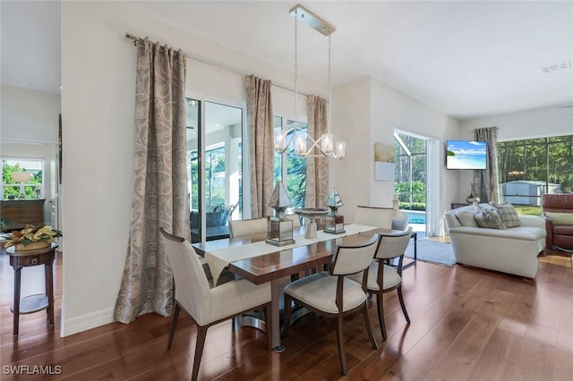 dining area with dark wood-type flooring and an inviting chandelier