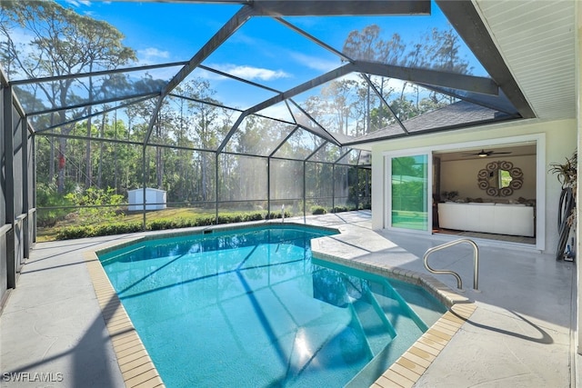 view of pool with ceiling fan, a shed, a patio area, and glass enclosure