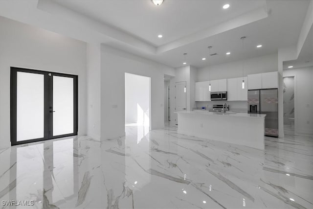 kitchen featuring sink, white cabinetry, hanging light fixtures, stainless steel appliances, and an island with sink