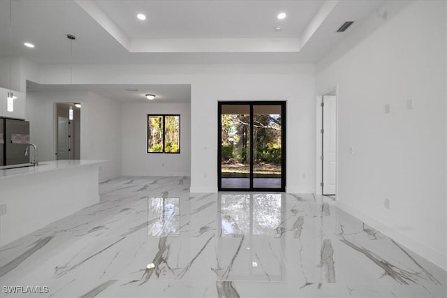 unfurnished living room with a tray ceiling and sink