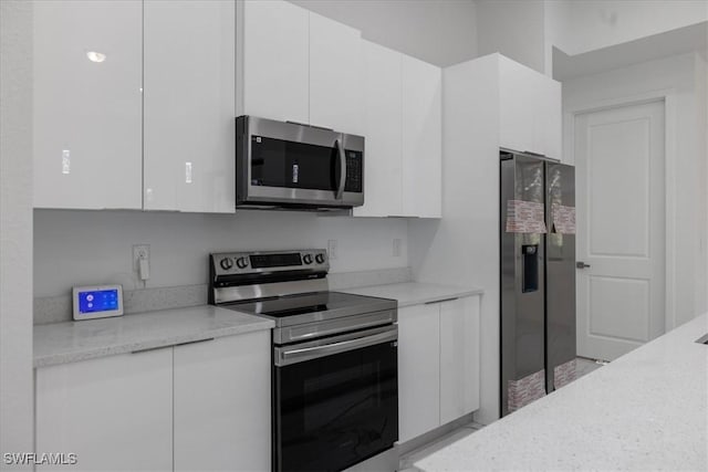 kitchen featuring white cabinetry, appliances with stainless steel finishes, and light stone counters