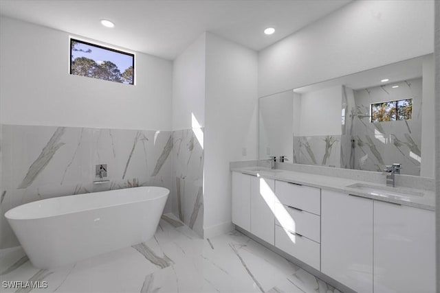 bathroom with vanity, a healthy amount of sunlight, and a bath