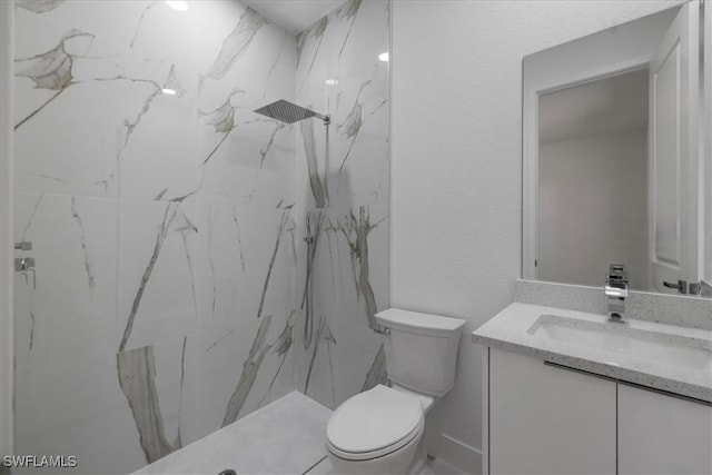 bathroom featuring a tile shower, vanity, and toilet