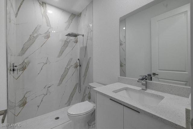 bathroom with vanity, tiled shower, and toilet