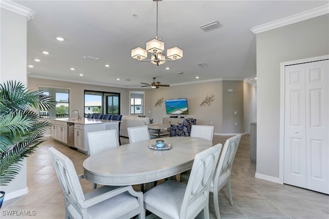 dining room featuring light tile patterned floors, ceiling fan with notable chandelier, ornamental molding, and sink